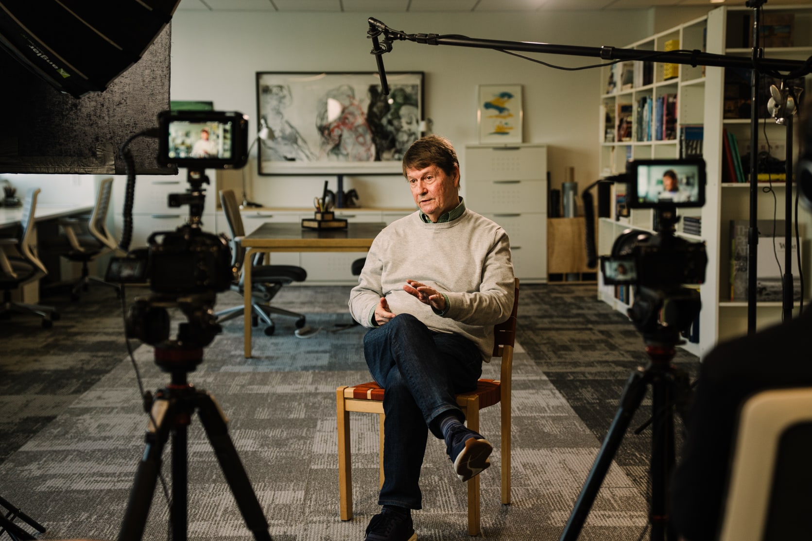 John Blackburn, founder of Blackburn Architecture, being interviewed for a documentary-style brand film at the firm's Washington, D.C. office. Storyteller Studios crew, two cameras, boom microphone, and lighting visible in frame.