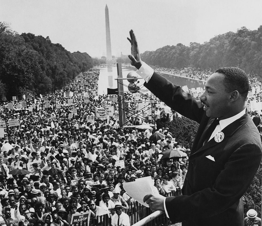 Martin Luther King, Jr., waves to the crowd gathered on the National Mall, the text of his "I Have A Dream..." speech in his hand.