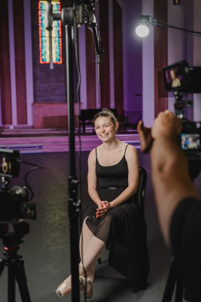 A Storyteller Studios Interview Subject, a ballerina in black, smiles and laughs with the producers.