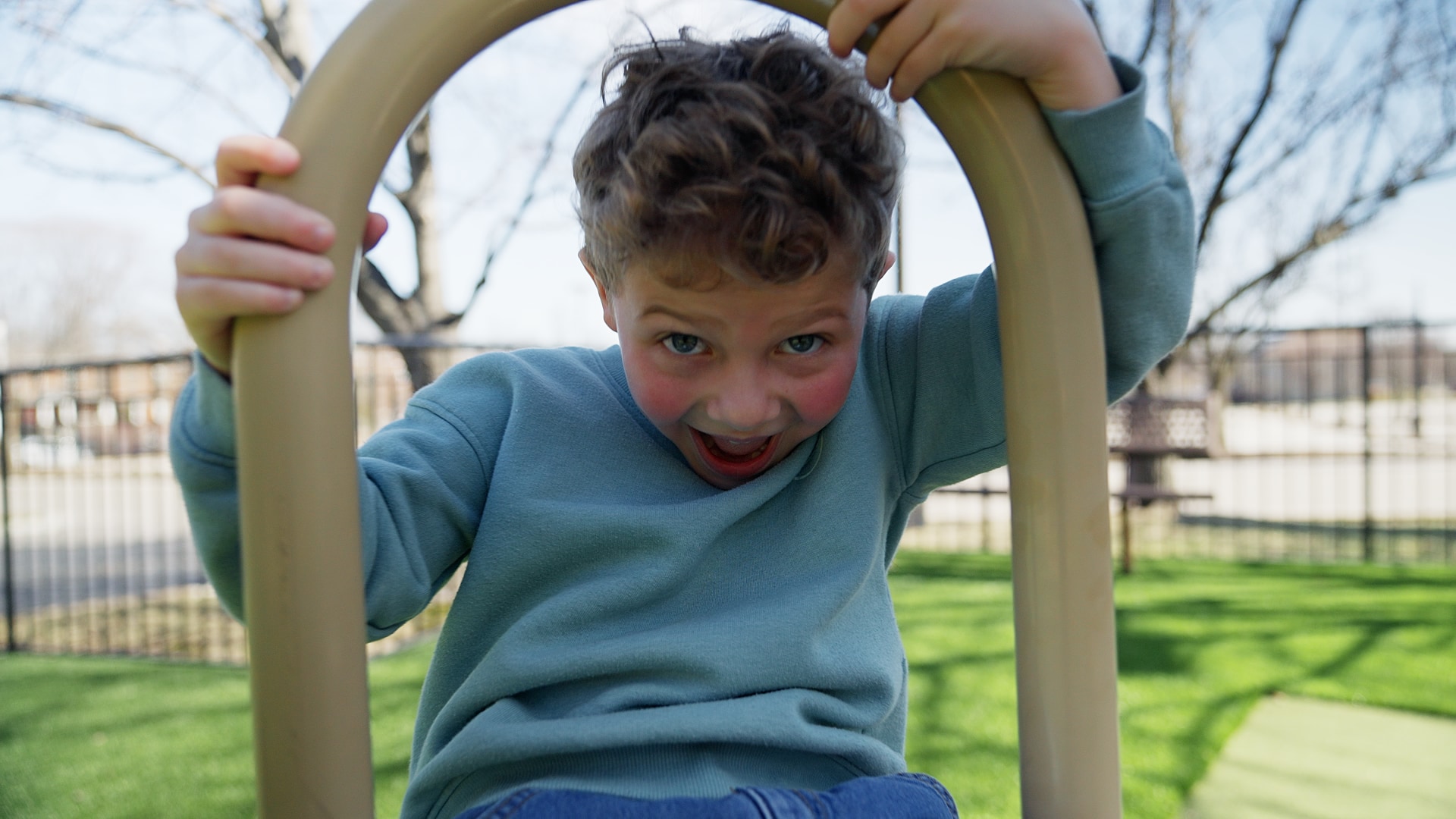 Bentlee, the young patient featured in HavenHouse St. Louis's 2026 HopeFest fundraising film, grins while playing on a playground.