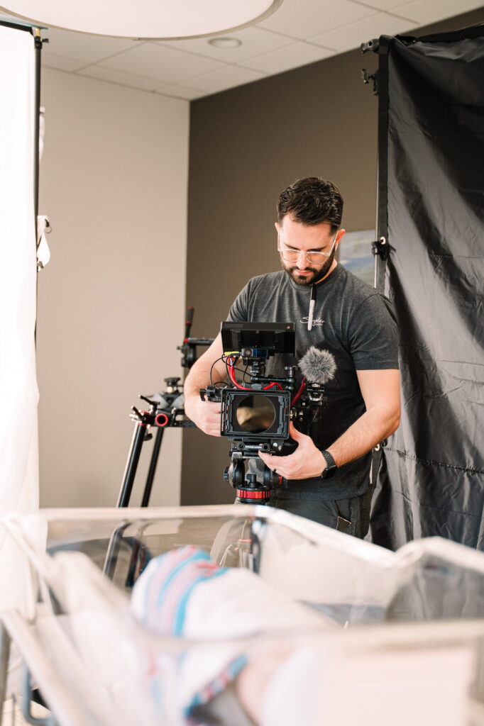 Storyteller Studios director Chris Costello lines up a shot over the bassinet on the hospital set of the IDPH newborn hearing screening PSA.