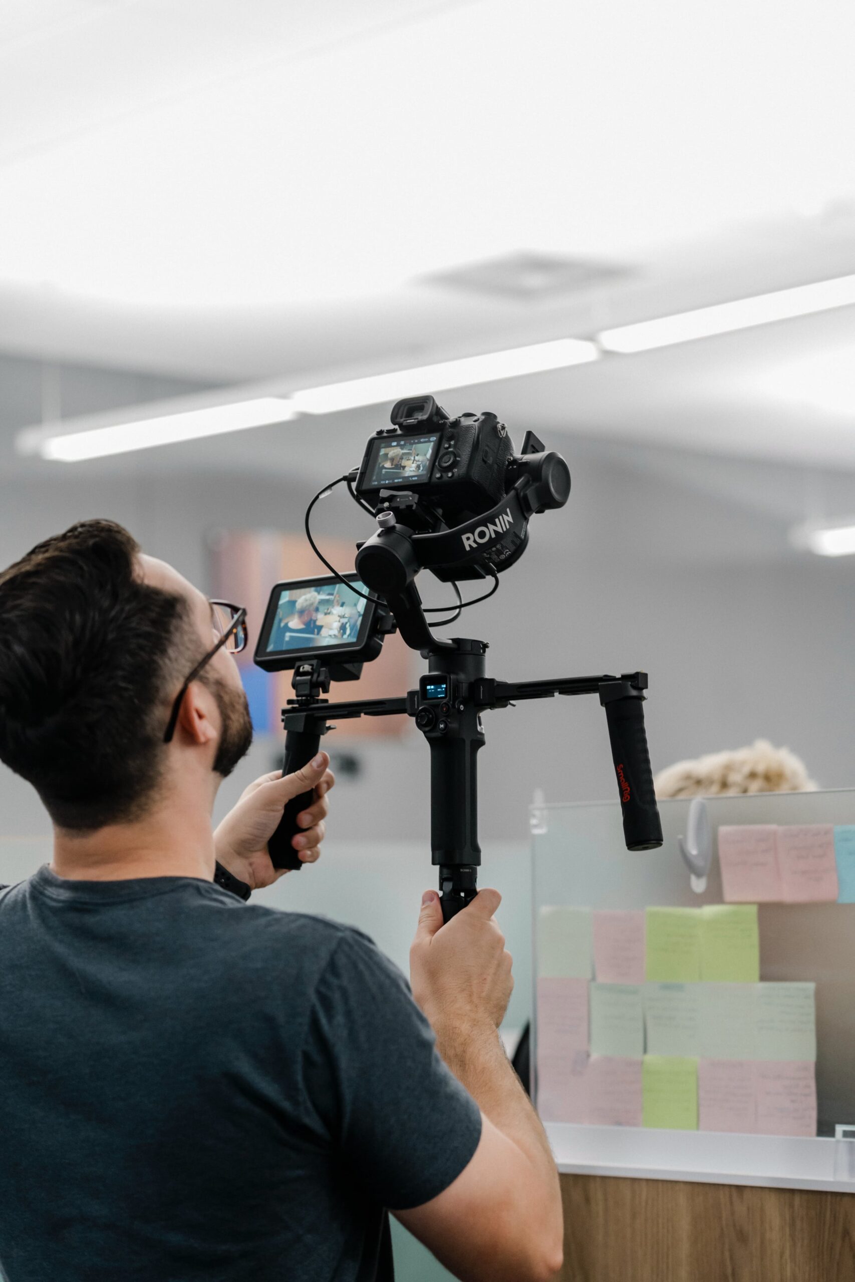 a male video producer operates a camera gimbal in a corporate office